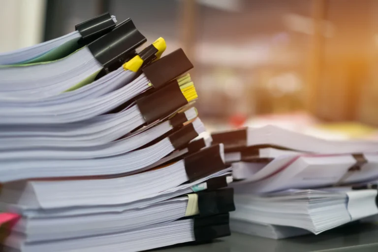 Stacks of clipped paperwork on an office desk, representing the volume of supporting documents involved while a DA works its way through council approval in NSW